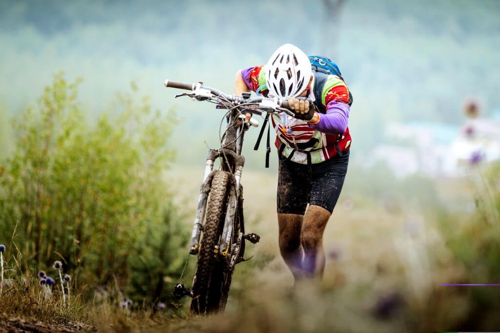 Cyclist going up a trail with his bike