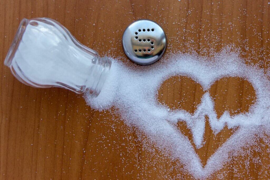 Shaker spilling salt into shape of ecg smiley face representing healthy salt for high blood pressure
