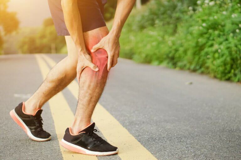 A jogger suffering from muscle cramps in his lower leg.