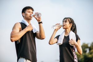 Active man and woman drinking water after workout using electrolyte powder for hydration