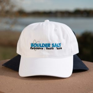 An adjustable white baseball cap embroidered with the Boulder Salt logo, perfect for showing your commitment to a healthy, active lifestyle