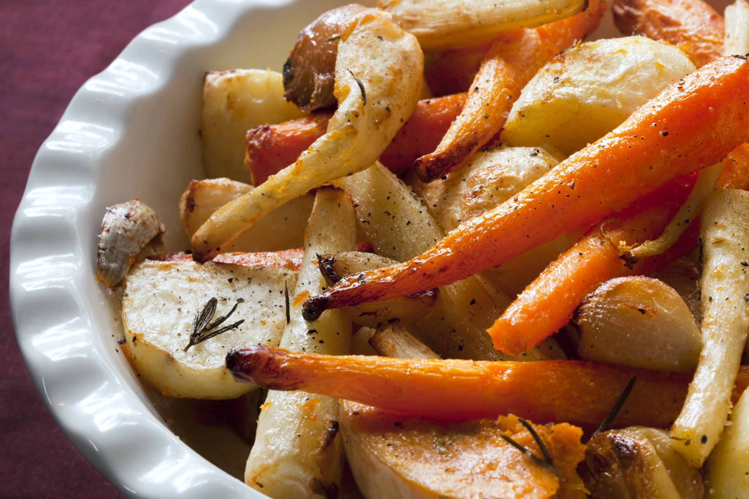 A bowl of roasted root vegetables, including carrots and parsnips, seasoned with Boulder Salt to enhance their natural flavors.