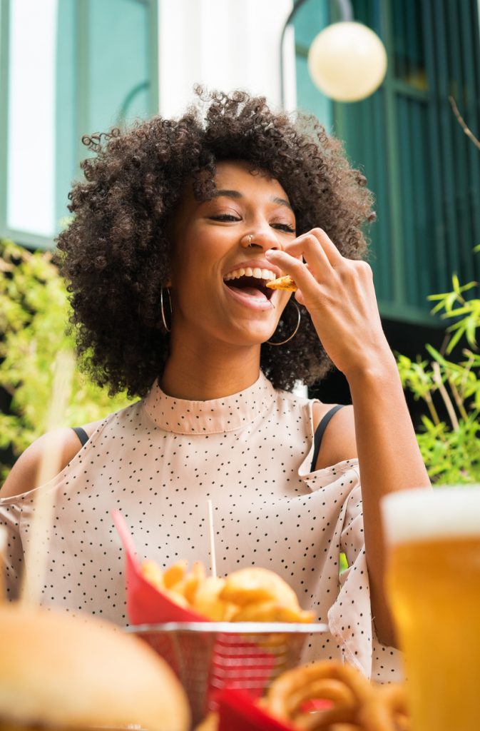 A happy restaurant customer enjoying a meal, illustrating how customers value the use of healthy, high-quality ingredients like Boulder Salt for a better dining experience
